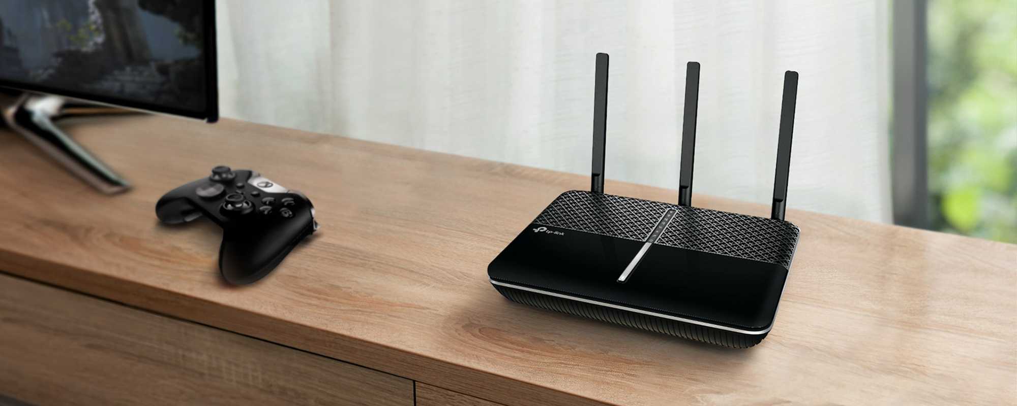 A black TP link wireless WiFi router placed on a wooden TV unit.
