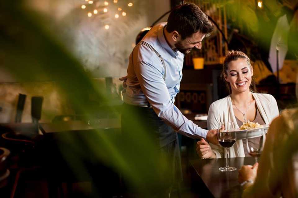 A woman being served a delicious meal by a waiter at a nice restaurant.