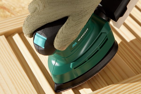 DIY home project with green hand sander being used on a wooden bench