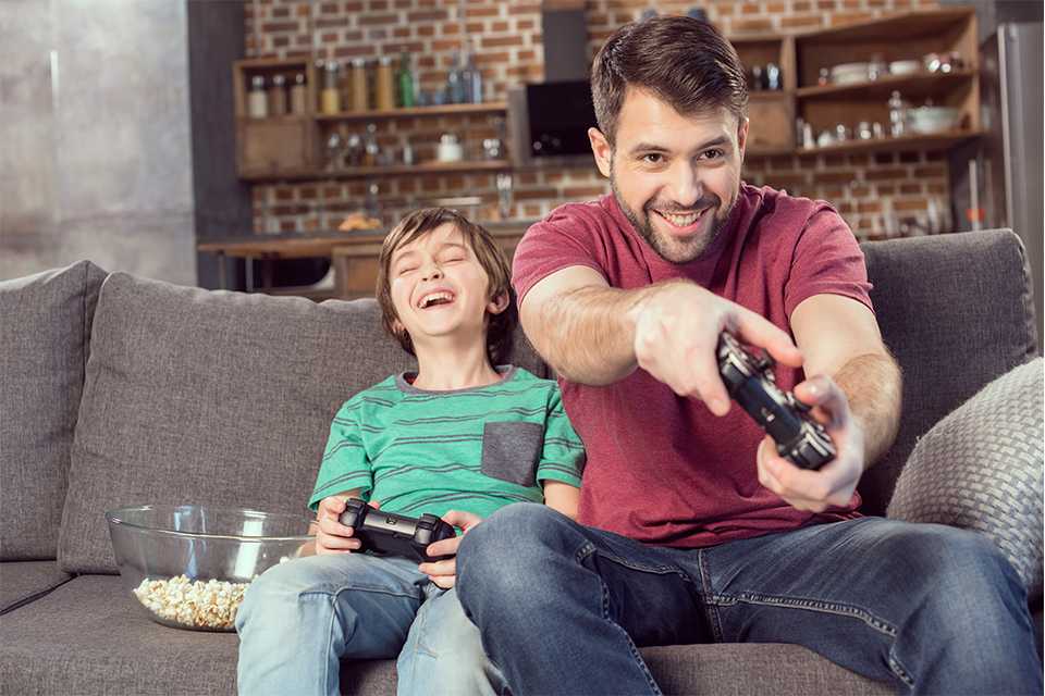 A boy and a man playing a video game sitting on a couch.