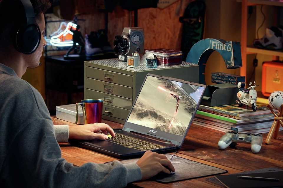 A man using ASUS TUF A15 15.6in Ryzen 5 16GB 512GB RTX2050 gaming laptop to play a game.