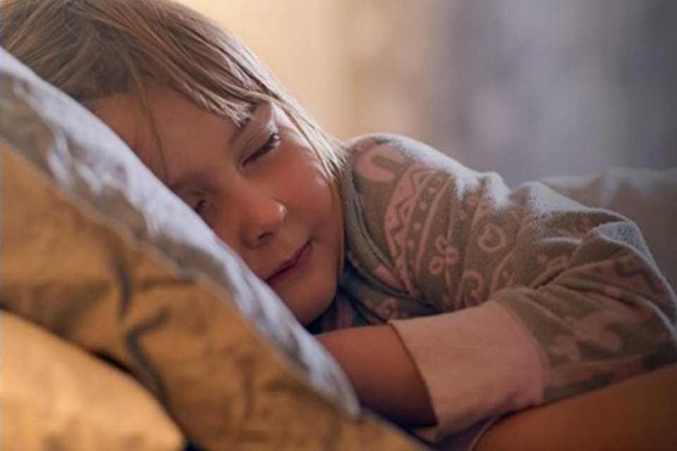 A child sleeping in the light of a Tapo L430C 2-pack E14 Smart Dimmable Multicolour Light Bulb.