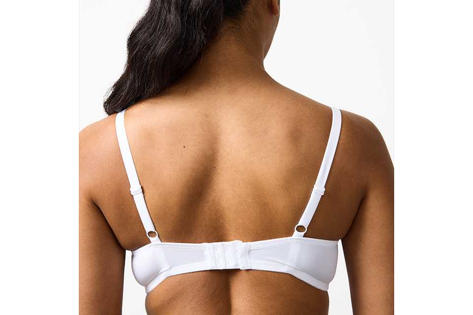 A woman wearing a white bra, with her back facing towards the image showing that her bra isn't riding up her back.
