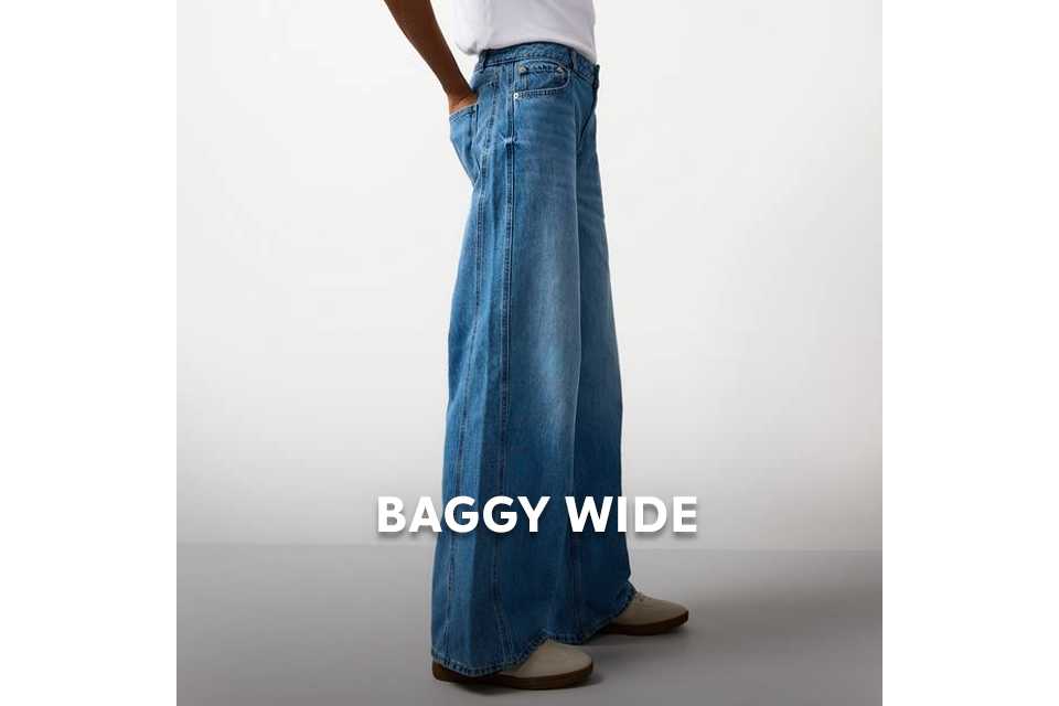 Model wearing wide‑leg baggy jeans in soft blue denim with a loose, relaxed fit.