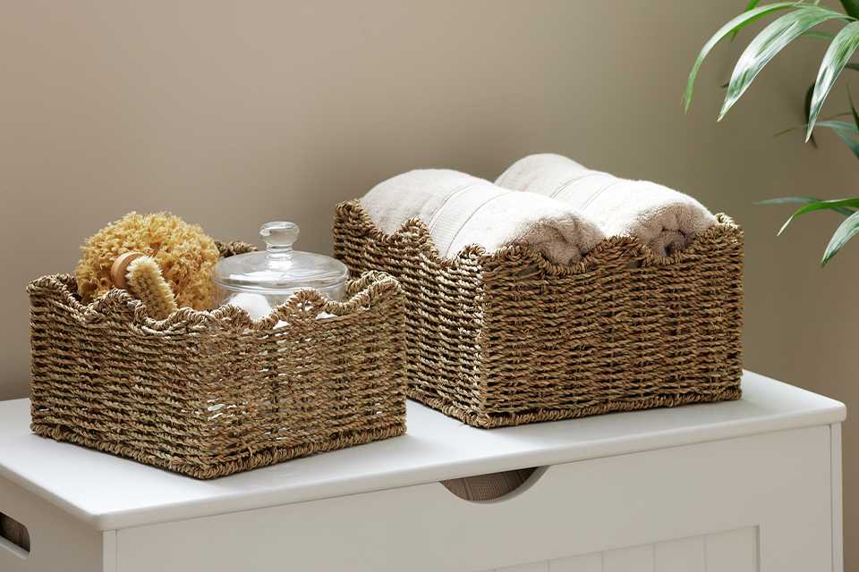 Habitat Pack of 2 Seagrass Wave Storage Basket in natural finish placed in a bathroom on a white storage unit.