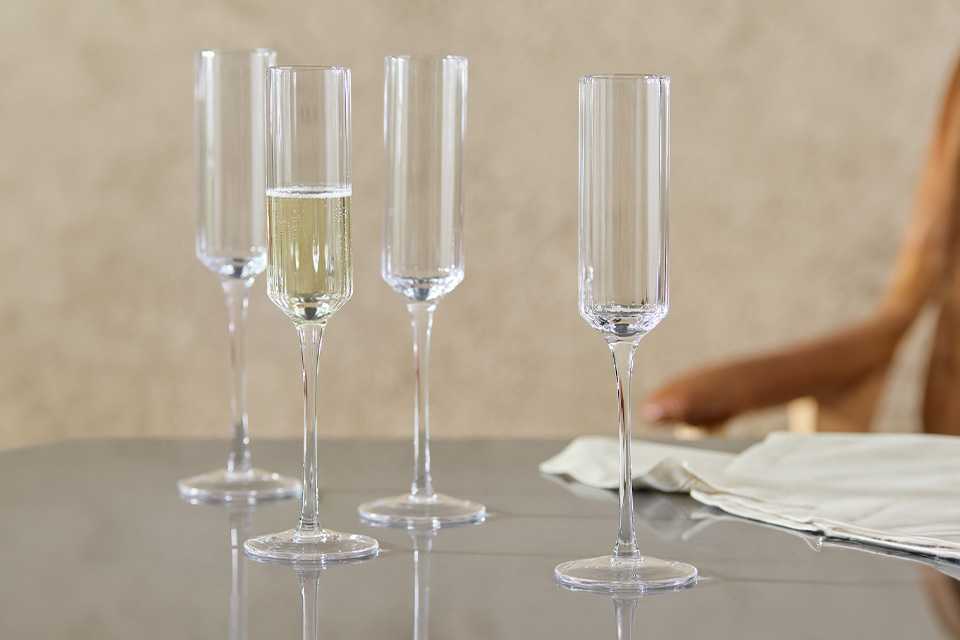 A set of 4 Habitat clear wilde ribbed champagne flute on a dining table.