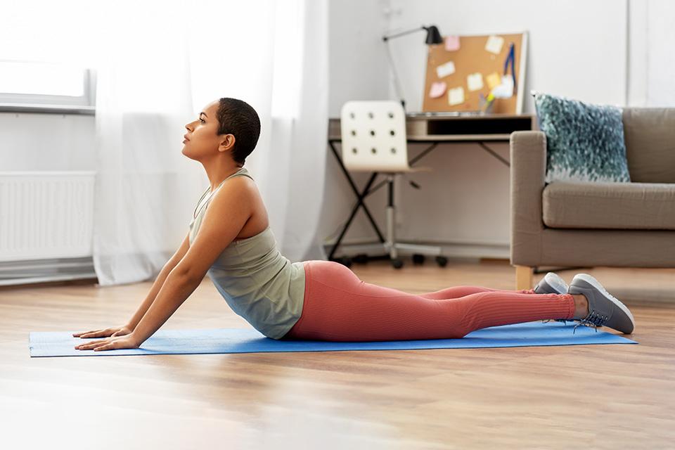 Woman doing cobra pose on yoga mat.
