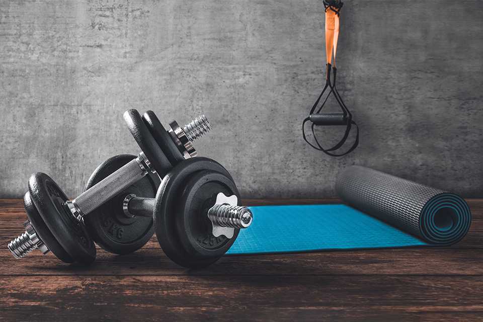 A set of dumbbells and a mat on the floor of a basement.