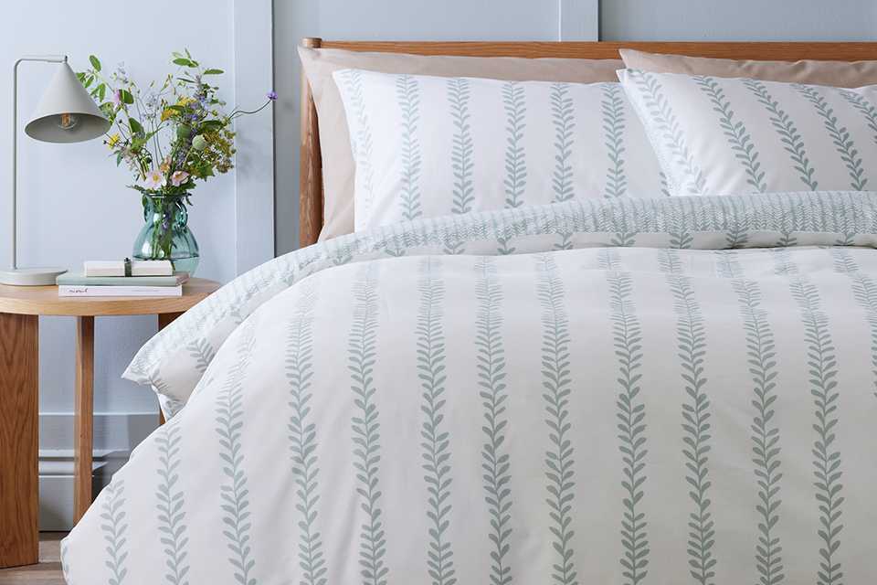 White and grey printed bedding on a mattress in a bedroom.