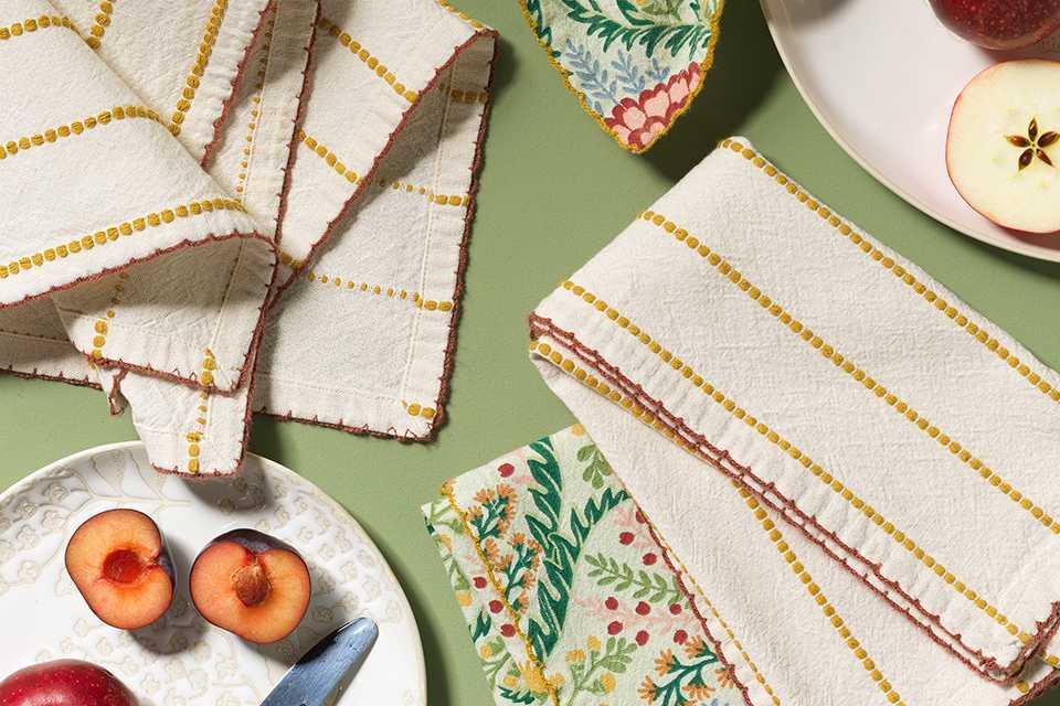 Floral printed plates with national trust tea towel set on green table.