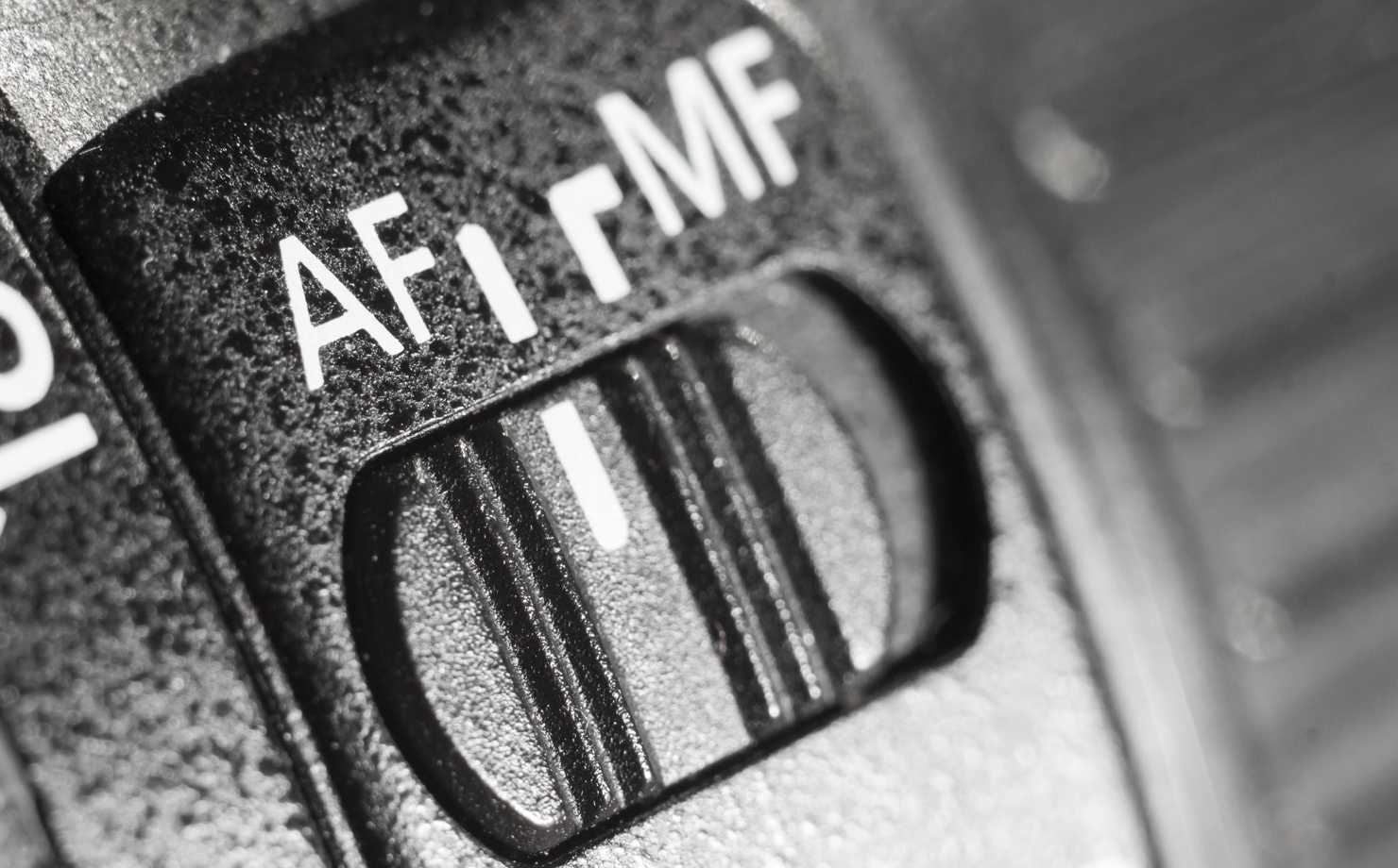 A black camera with an autofocus and a manual focus button on it.