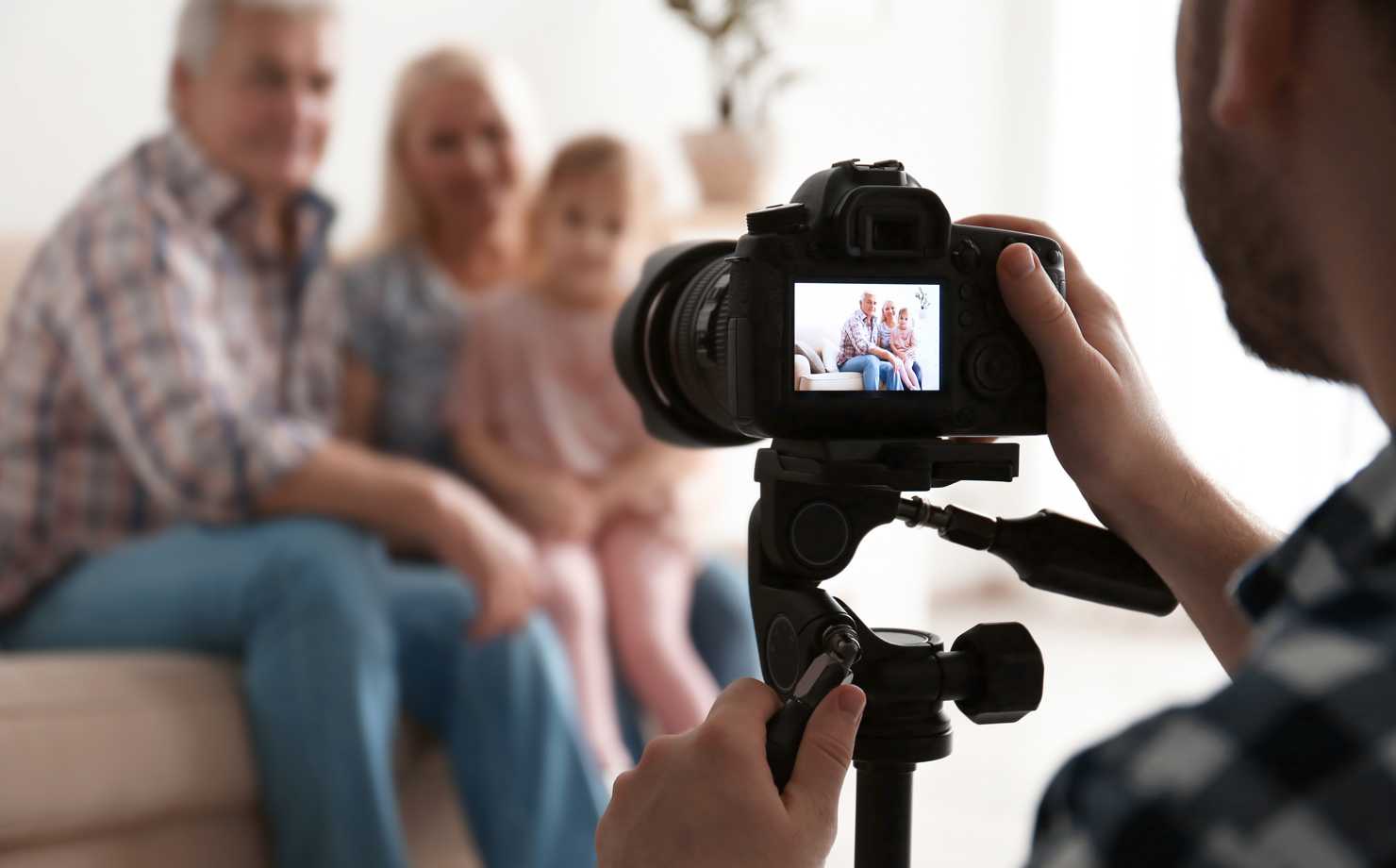 A person clicking a family portrait photo using a black camera on a tripod.