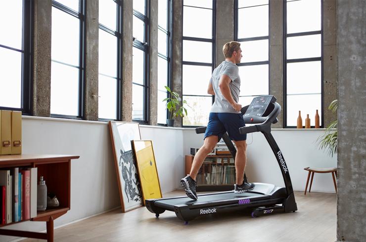 A man running on a treadmill in his house.