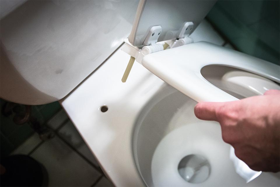 A toilet seat being lifted off.