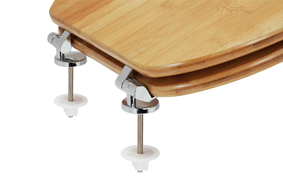 A toilet seat lined up over screws and fittings.
