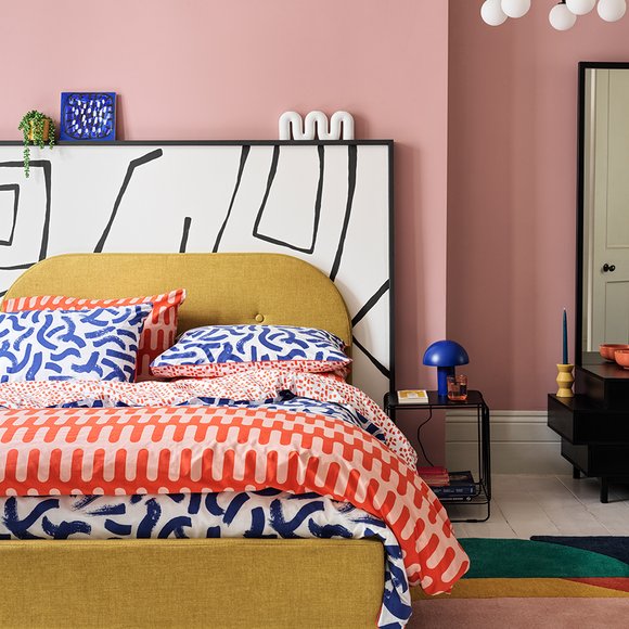 Yellow bedframe with blue and orange bedding.