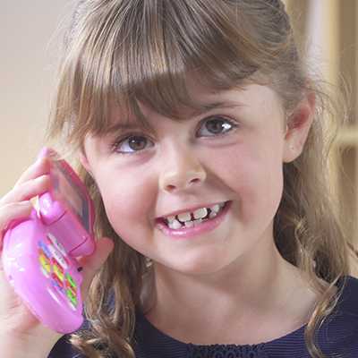 A girl playing with a Peppa Pig Flip & Learn Phone.