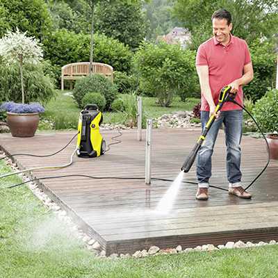 A man using a pressure washer in his garden.