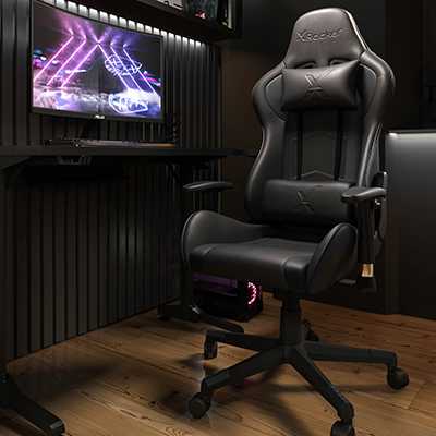 A black gaming chair next to a PC on a desk.