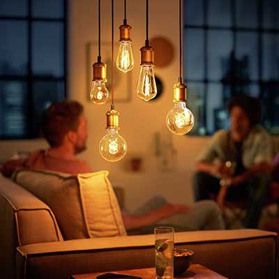 A room lit up with lightbulbs with people seated in the background.