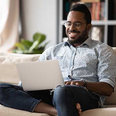 A man sitting with his laptop on a couch.