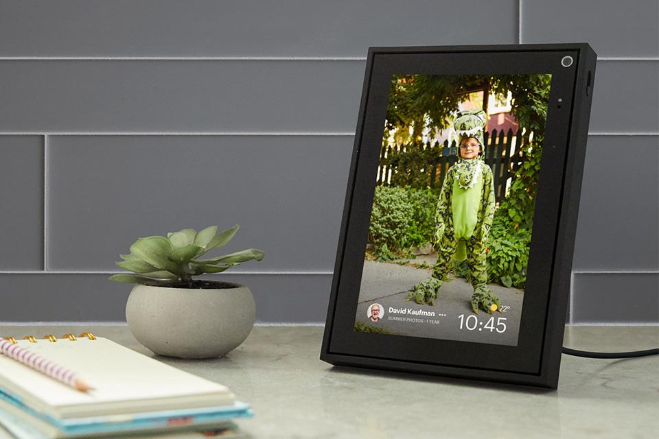 A Portal screen shows the view from a front door, with a woman standing outside and a man wheeling a bicycle coming up the path behind.