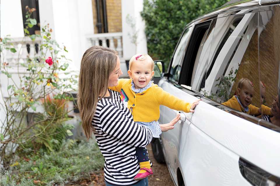 A mother getting her baby ready for a car journey in a Joie car seat.