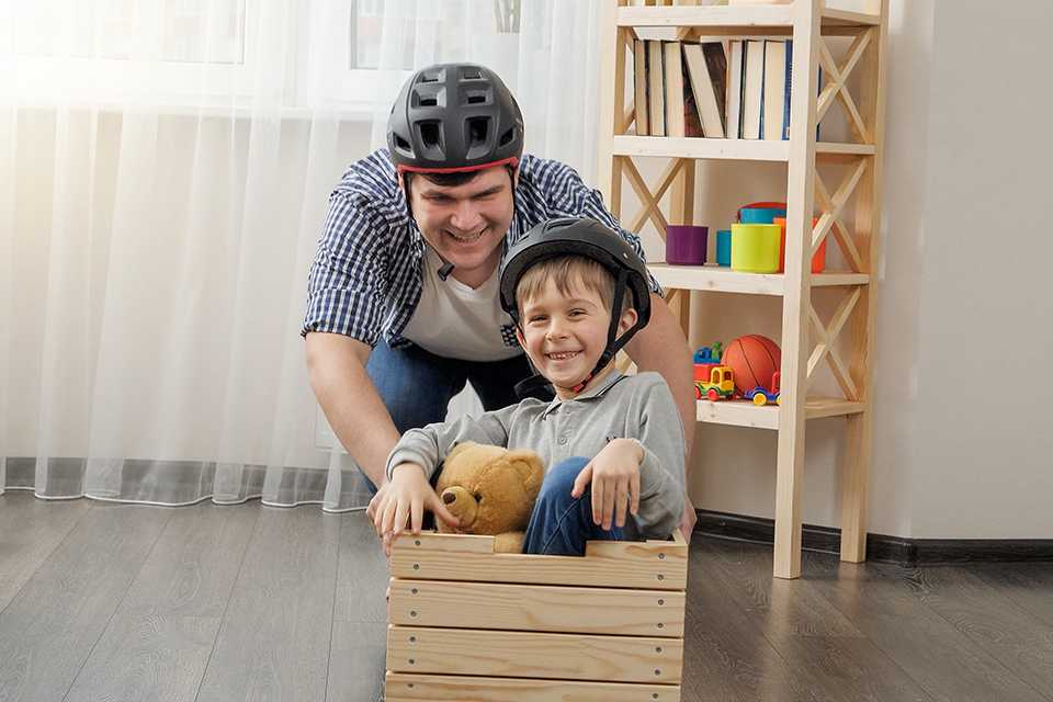 A father-son duo playing with a toy crate with wheels.