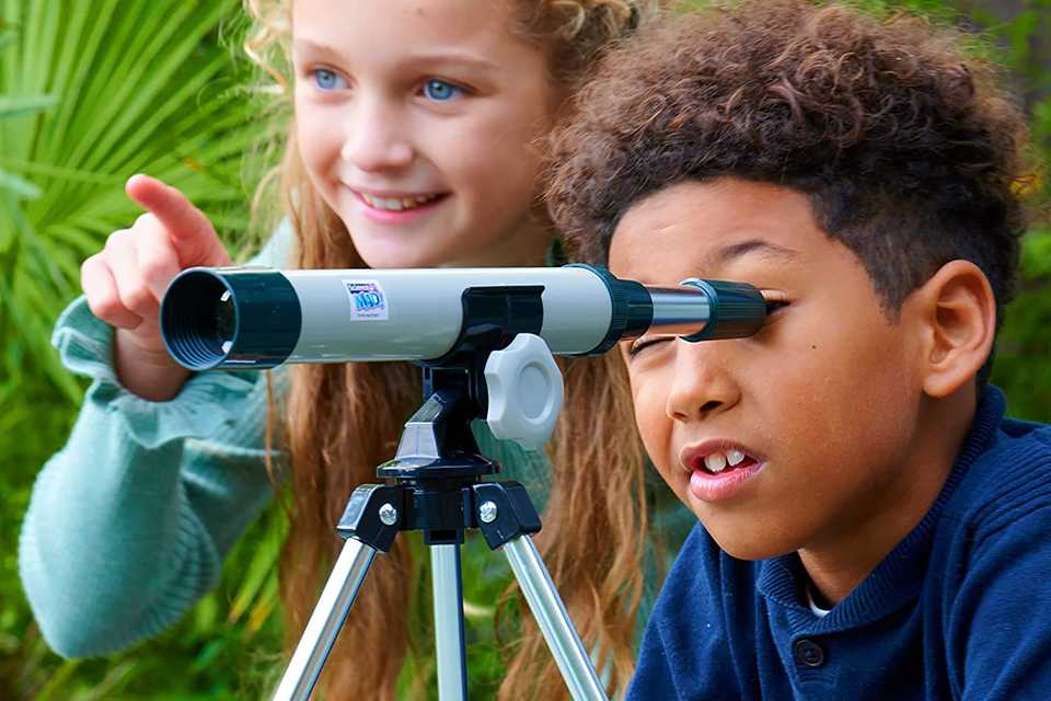 Two kids playing with a Science Mad 30mm Telescope with Tripod.