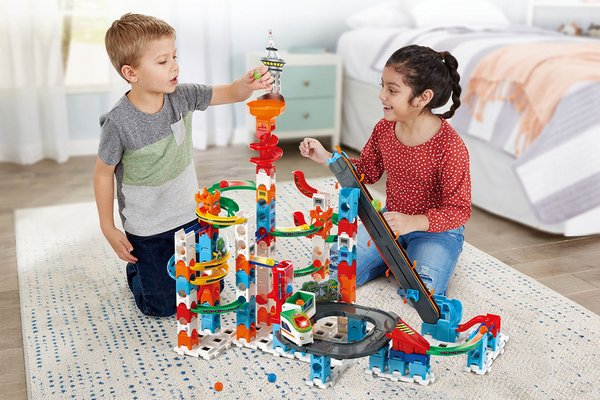 Two kids playing with a VTech Super Sky Tower.