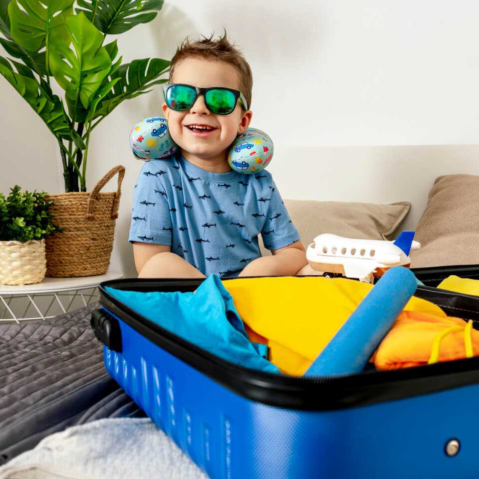 Child wearing sunglasses beside a suitcase