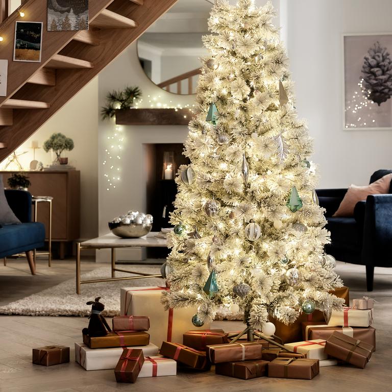 Large green christmas tree with gold decorations and christmas presents underneath the tree.