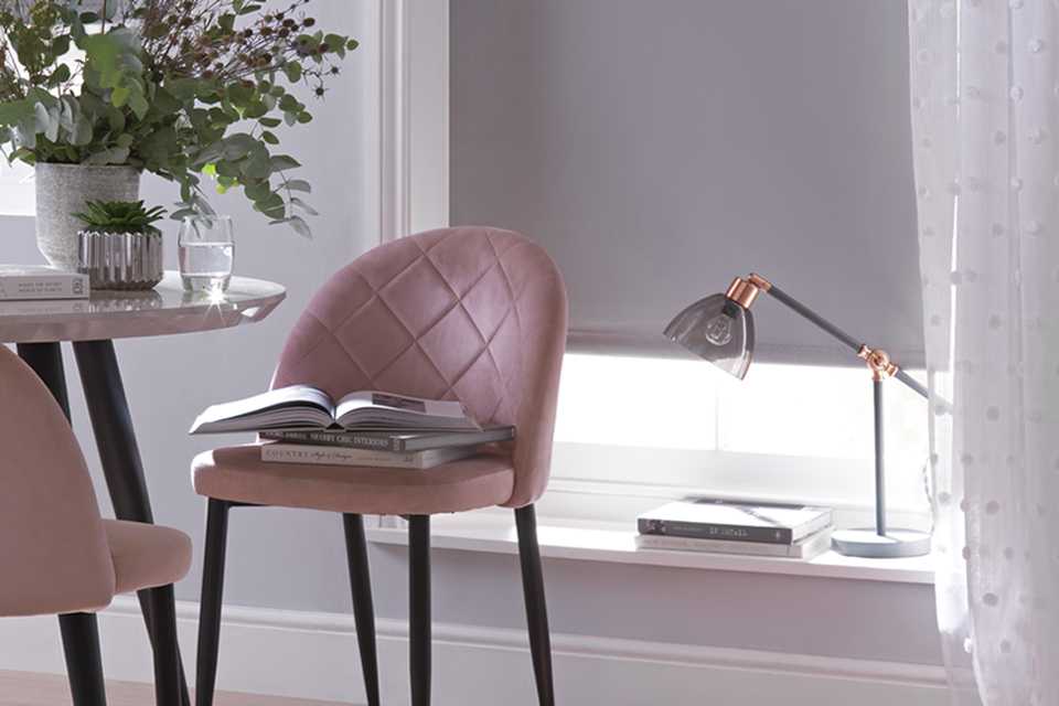 Dining room with pink velvet sofas and a blind with voile over the top.
