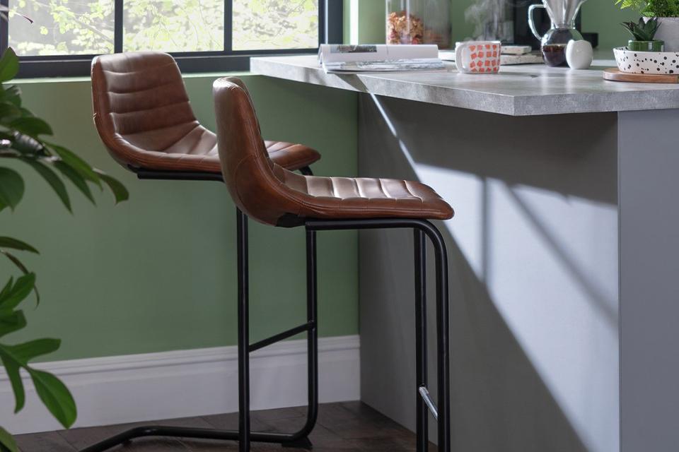 A pair of Habitat faux leather cantilever barstool in tan.