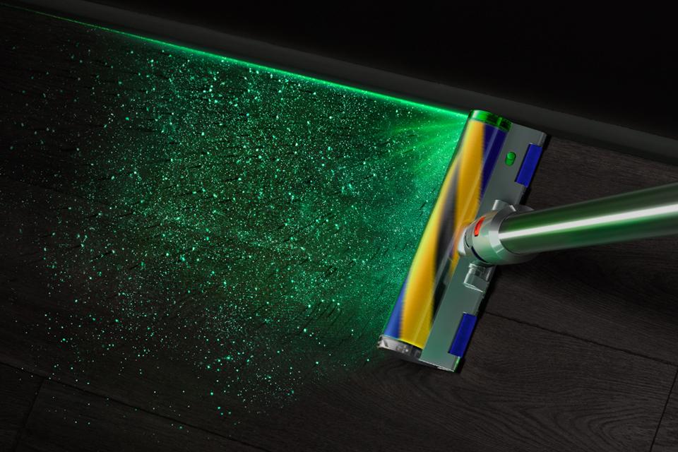 Dyson V15 Detect's cleaning head emitting laser to spot invisible dust particles on the floor.