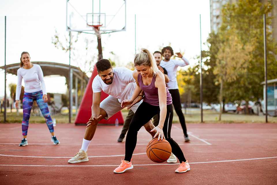 A group of friends playing basketball on a sunny day.