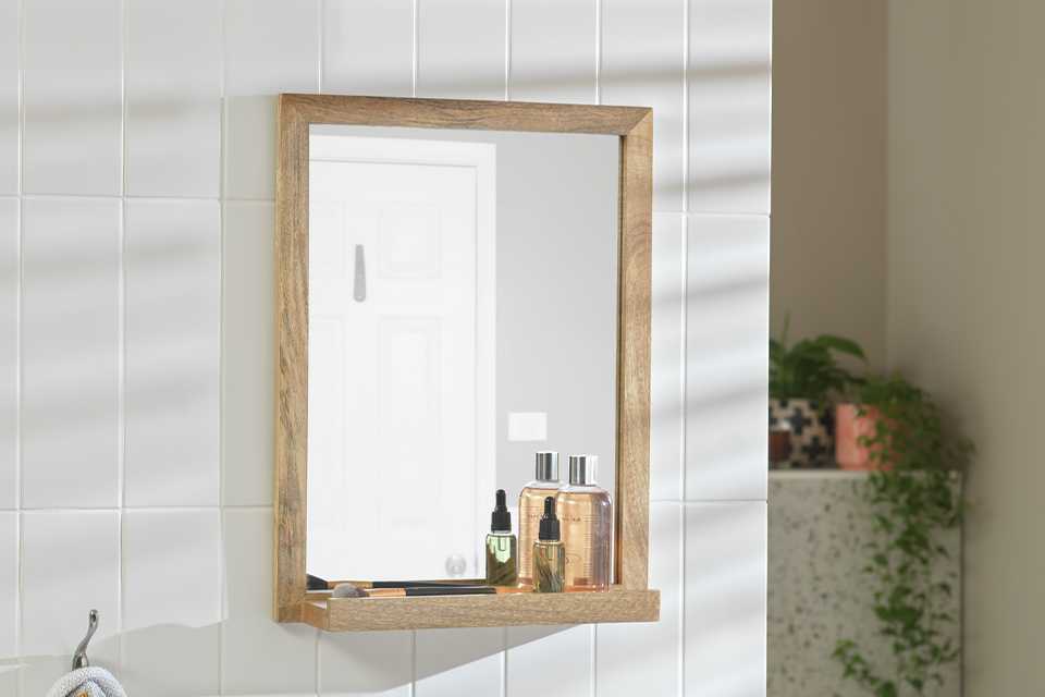A Habitat Mango Wood Bathroom Mirror with Shelf in a bathroom.