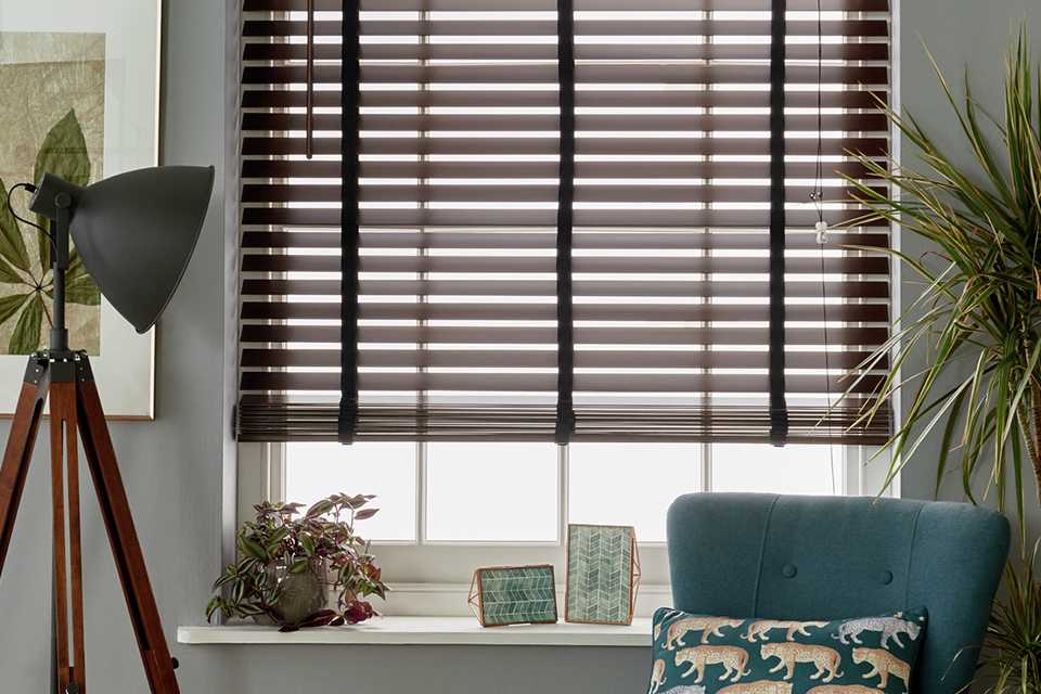 A wooden blind on the window of a living room.