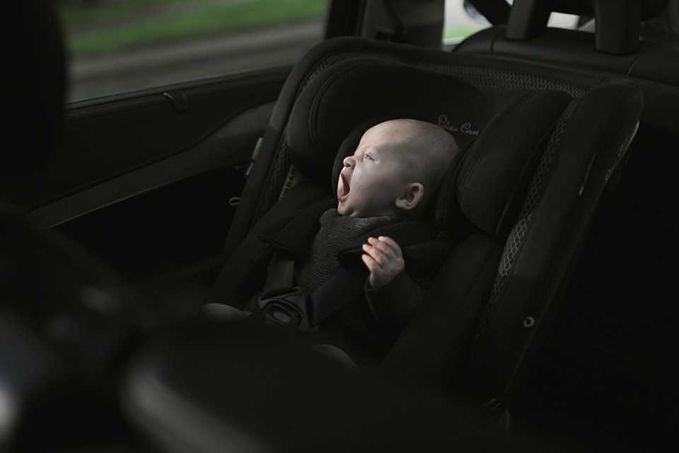 A baby yawning, comfortably tucked in a Silver Cross Motion All Size 360 car seat.