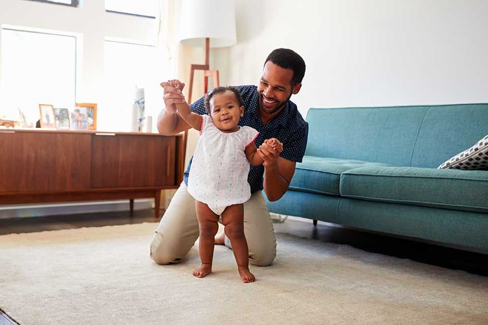 A father playfully helping his daughter walk.