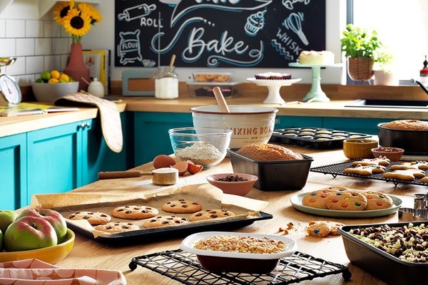 A kitchen counter with several baked items including 2 different types of cookies.