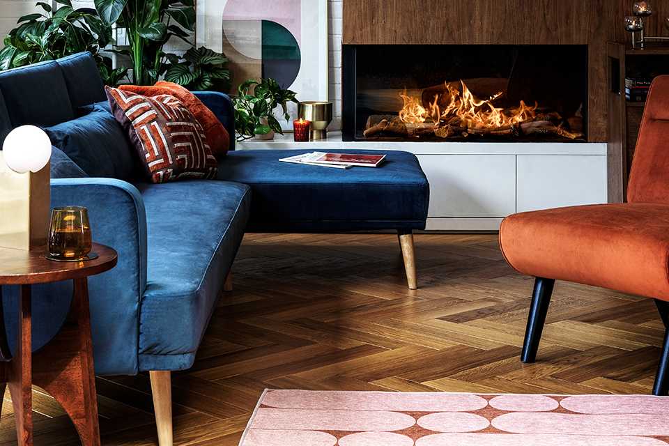 A blue sofa in front of a rust-coloured armchair in a living room.