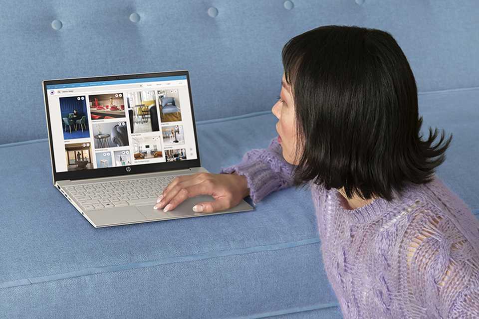 A woman looking at an HP laptop placed on a sofa.