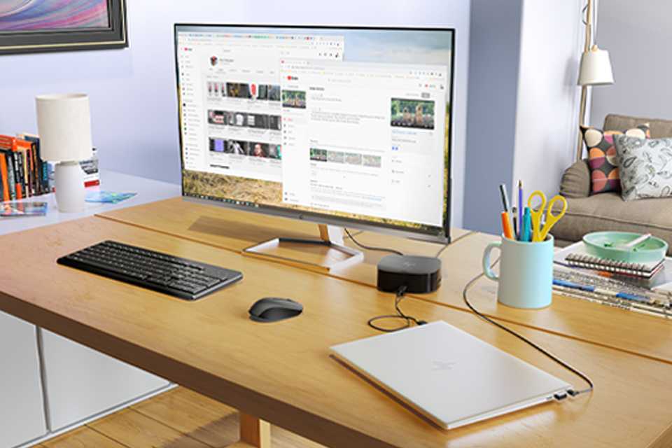 An HP monitor placed on a desk next to a wireless keyboard, a mouse and a laptop.