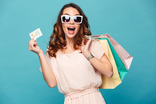 A lady holds a gift card and 3 shopping bags.