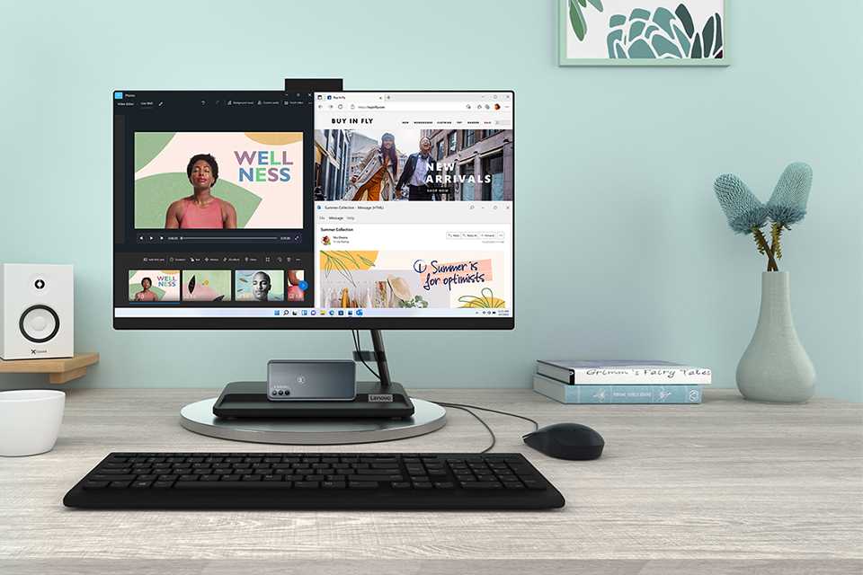 Lenovo IdeaCentre on a desk with turquoise background along with books, vase, a cup, and a speaker next to it.
