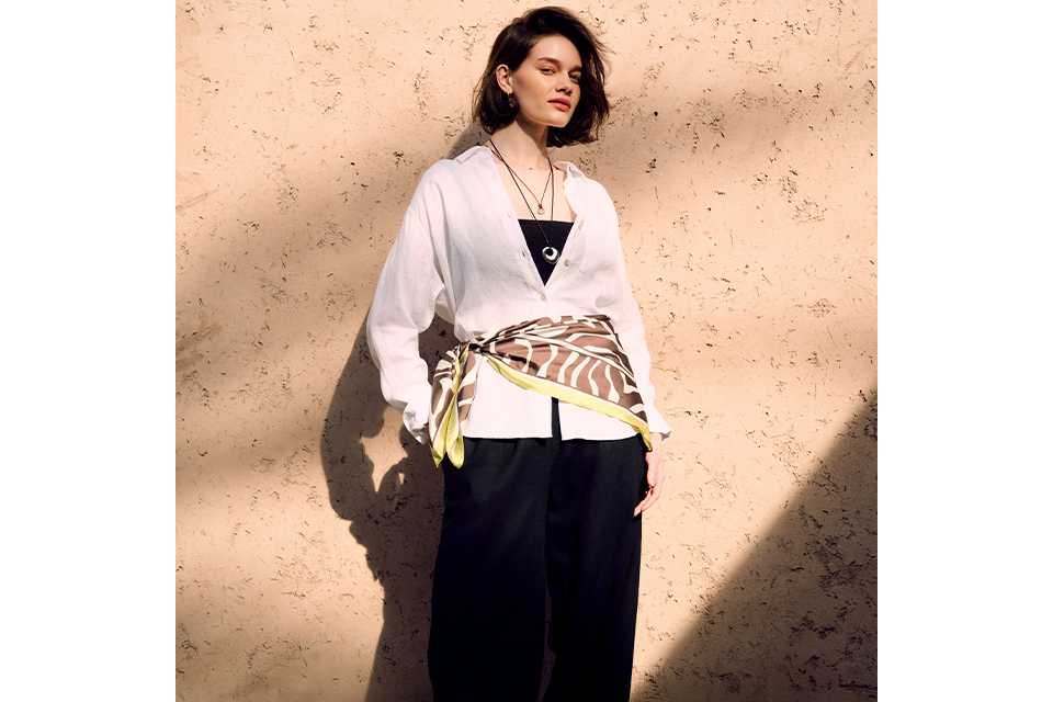 Light yellow short‑sleeve button‑front midi dress styled with a brown knit layered over the shoulders on a clean studio background.