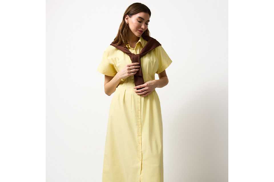 White lightweight button‑through shirt styled with black wide‑leg trousers and a brown patterned scarf tied at the waist in an outdoor setting.