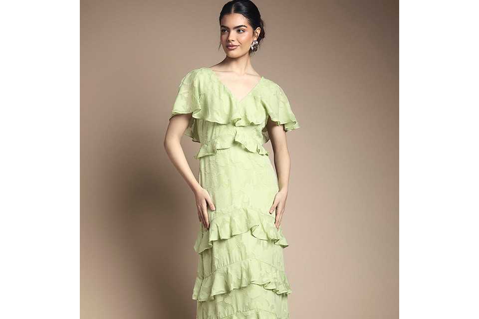 Light green ruffle tiered midi dress with short flutter sleeves and V‑neck, styled with white strappy sandals on a neutral background.