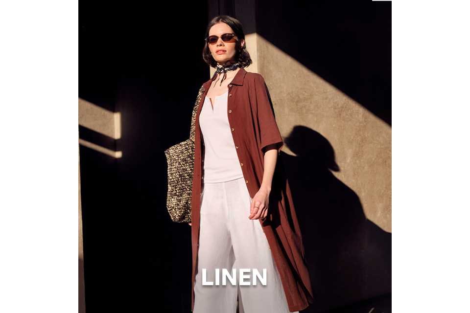 Relaxed summer outfit with a rust‑coloured lightweight coat, white top and wide‑leg trousers.